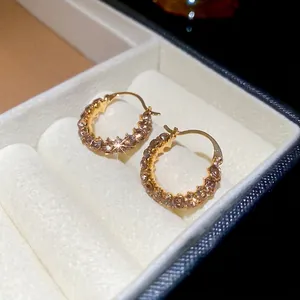 Elegante geometrische Goldohrringe mit Champagner-Steinen auf weißem Samtgrund