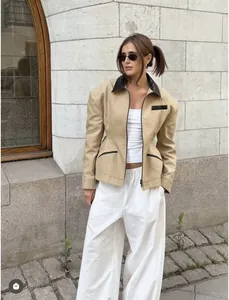 Close-up of khaki jacket with black leather collar trim and waist-cinching detail