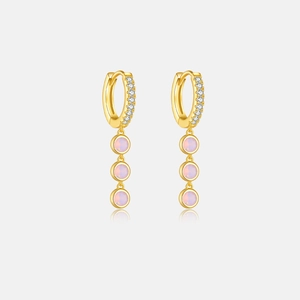 Detail of gold hoop earrings featuring white pavé stones and triple pink gemstone charms