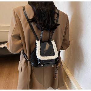 Detail of a vintage black leather backpack with white faux shearling trim and woven tassel