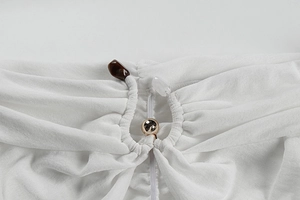 Détail du tissu blanc plissé avec des perles d'ambre, blanches et dorées élégantes