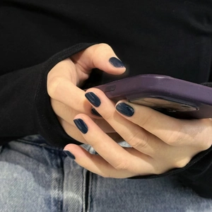 Eleganti unghie finte blu navy mostrate sulla mano di una modella in una posa naturale
