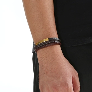 Close-up of multilayer braided leather bracelet with gold metal plates on model's wrist