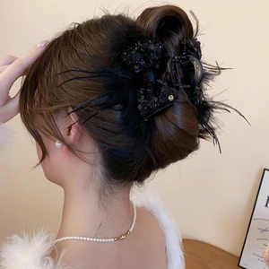 Rear view of a black sequin bow hair claw clip with feather details on model's hair