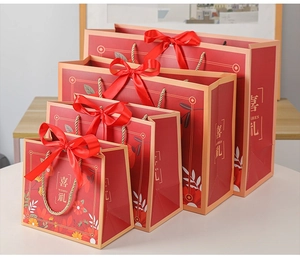 Detailed comparison of four sizes of red gift bags with gold handles and ribbons