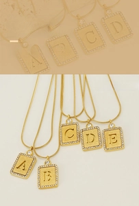 Détail macro du collier lettre plaqué or 18k avec finition mate et cristaux pavés