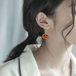 Festive Halloween pumpkin earrings in vibrant orange worn by a model for size visual