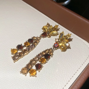 Detailed view of French flower drop earrings with multicolored crystals and gold setting