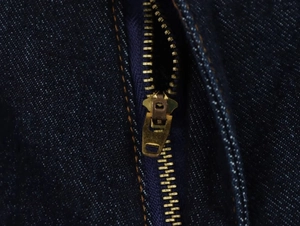 Détail de la fermeture éclair dorée sur l'ensemble en denim bleu foncé pour femme