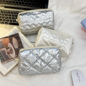 Detail showing heart-quilted and diamond-patterned PU leather makeup bags in silver and white