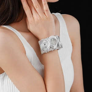 Detail of silver spiral multilayer wrap cuff bracelet on model wrist with black background
