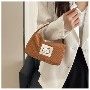 Detailed close-up of brown corduroy handbag with cute cartoon bear patch and fanyu logo