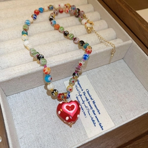 Macro view of colorful beaded necklace featuring a red heart pendant in a wooden jewelry box