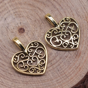 Close-up of golden heart-shaped filigree pendants with swirl texture on a wooden surface