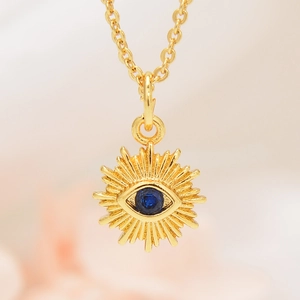 Macro detail of gold evil eye sunflower necklace pendant with blue cubic zirconia