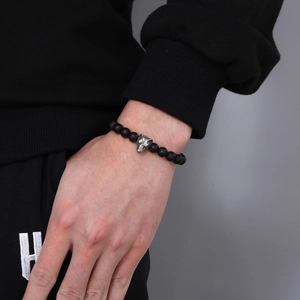 Detail shot of a matte black agate beaded bracelet featuring a silver wolf head on a male wrist