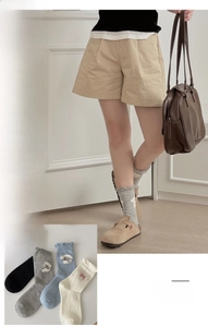 Detail of knit crew socks with cute dog embroidery and stylish rolled cuffs in four colors