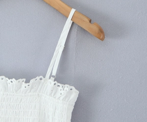 Détail rapproché du caraco en coton blanc avec broderie dentelle et buste smocké élastique