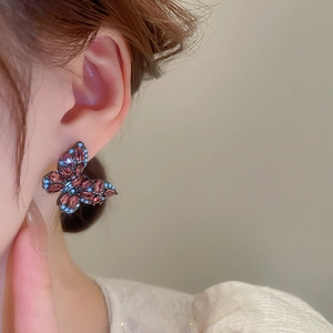 Macro side view of butterfly stud earrings with purple marquise gems and blue accents