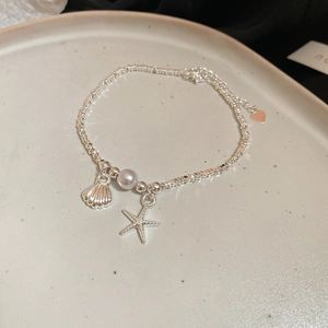 Dettaglio del bracciale in argento tema oceano con ciondoli stella marina e conchiglia