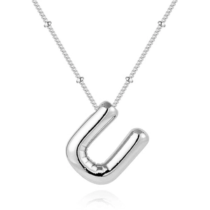 Macro detail of silver balloon letter U pendant on a dainty beaded chain necklace