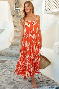Detail of a vibrant orange A-line maxi dress with white leaf print and tiered hemline