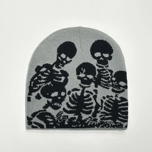 Detail of knitted beanie showing the intricate black skull jacquard pattern on grey fabric