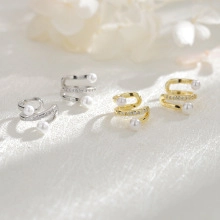 Detail of three-layer spiral ear cuffs with white pearls in gold and silver finishes