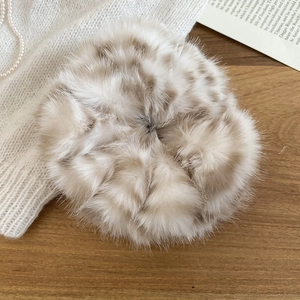 Dettaglio di un elastico in peluche con stampa leopardata su fondo in legno