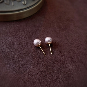 Macro shot of elegant pinkish-brown pearls with gold pins on dark brown velvet fabric
