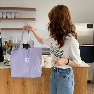 Close-up of a purple canvas tote bag with a white minimalist square label decoration