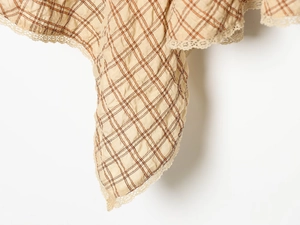 Detail of beige plaid fabric with delicate lace trim on a stylish short dress