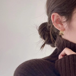 Elegant gold minimalist curved stud earrings for women shown worn on a model ear
