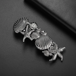 Vintage silver ocean star and seashell spring hair clip on dark textured surface