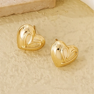 Macro detail of 3D gold heart earrings with polished finish on textured stone
