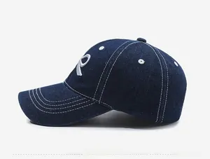 Side view of dark blue denim baseball cap featuring white R embroidery and contrast stitching