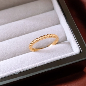Macro shot of gold beaded ring texture displayed in a grey velvet jewelry box slot