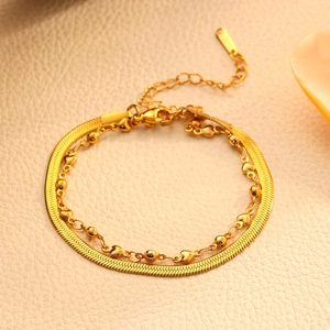 Détail du bracelet multicouche doré avec chaîne serpent plate et pendentif en cœur