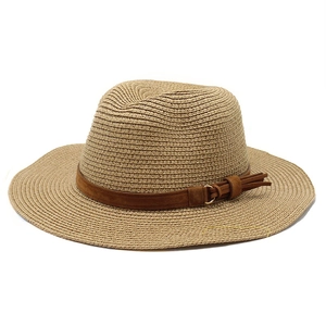 Detail of straw sun hat with dark brown suede band, tassel knot, and gold ring accents