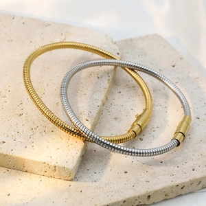 Detail of gold and silver herringbone chain bracelets on textured stone surface