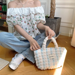 Detail of blue and white checkered quilted handbag with woven label on summer outfit