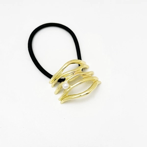Close-up of golden hollow wave alloy ponytail holder with a white pearl on white background