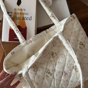 Detailed shot of quilted cotton tote bag featuring floral bear prints and inner woven label