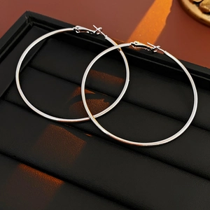 Close-up of classic silver round hoop earrings on a professional black jewelry display tray