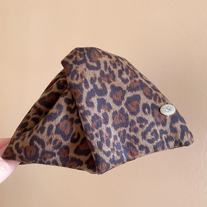 Detail of leopard print fabric hair clip featuring a gold oval metal buckle ornament