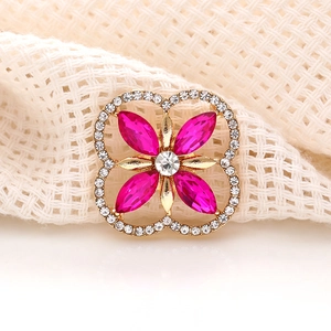 Macro view of a gold quatrefoil flower charm with magenta crystals and clear rhinestones