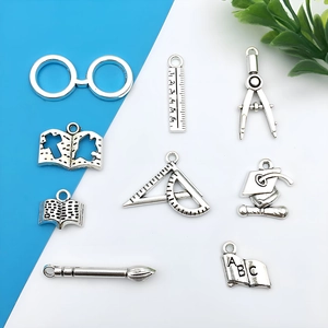 Detailed view of silver antique alloy school charms including graduation hat and glasses