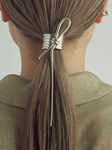 Macro detail of a silver metallic knot hair clip styling a low ponytail for women