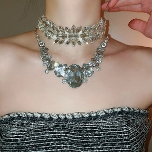 Detail of layered silver-toned rhinestone necklaces with large oval crystal on model