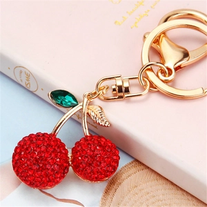 Llavero de cereza roja brillante con detalles dorados y diamantes de imitación
